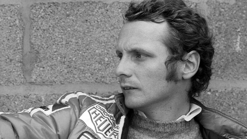 Niki Lauda sits against a wall at the 1975 British Grand Prix