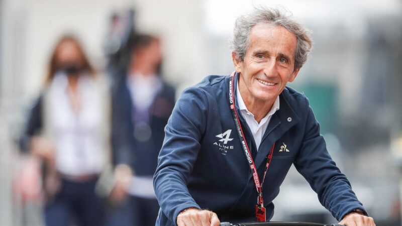 Alain Prost in F1 paddock on a scooter