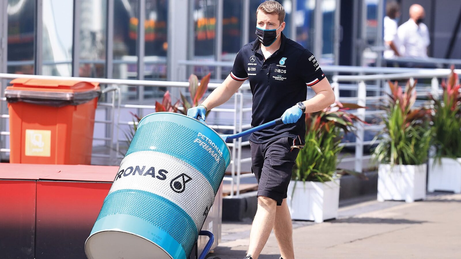 Mercedes F1 team member pushes a Petronas fuel barrel