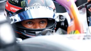 George Russell stares out from his crash helmet in the cockpit of his Mercedes F1 car