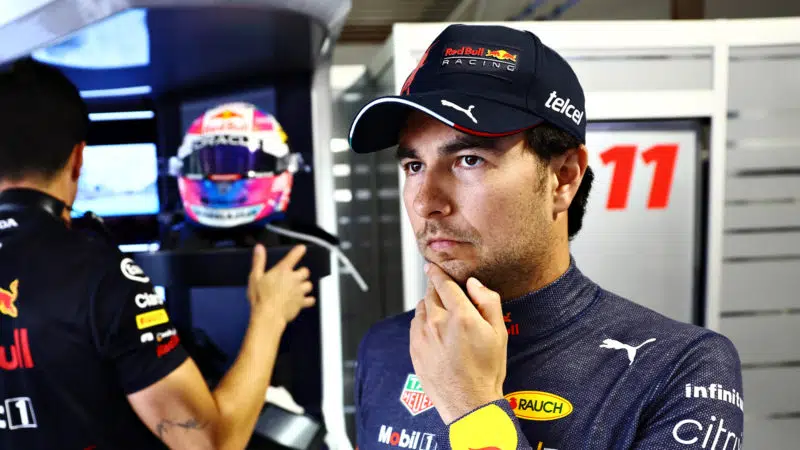 Sergio Perez with hand on chin in the Red Bull pits
