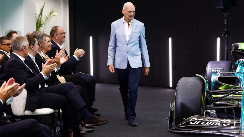 Adrian Newey walks past Aston Martin F1 car at press conference