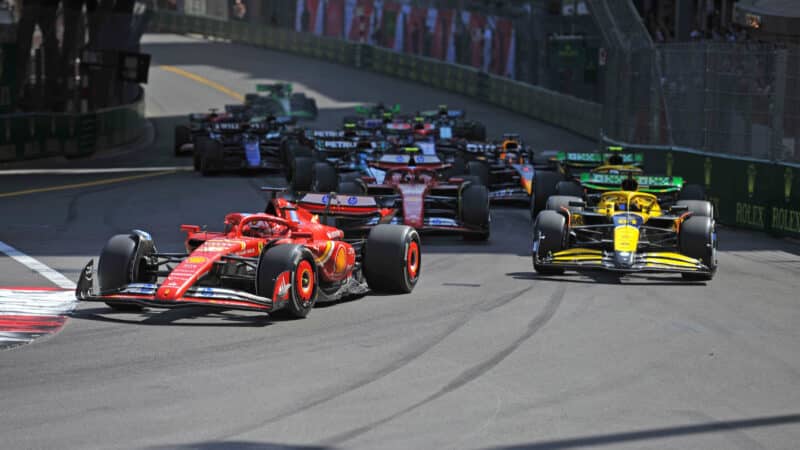 Charles Leclerc (Ferrari) leads Oscar Piastri (McLaren-Mercedes) and the rest of the fiield into the first corner after the start ofthe 2024 Monaco Grand Prix in Monte Carlo