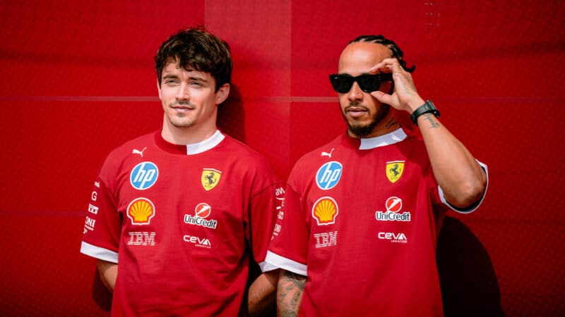 Charles Leclerc and Lewis Hamilton against red wall of Ferrari F1 pit garage