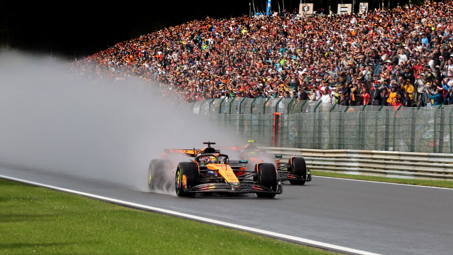 Oscar Piastri takes the lead from McLaren-Mercedes teammate Lando Norris on the first lap of the wet the 2025 Belgian Grand Prix