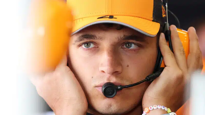 Lando Norris wearing headphones in McLaren F1 pit garage