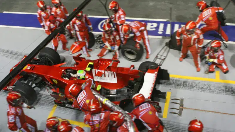 Felipe Massa (Ferrari) exits the pits with the fuel hose and a mechanic still attached to the car in the 2008 Singapore Grand Prix