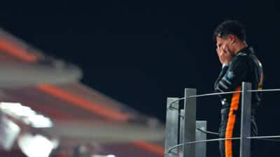 Lando Norris holds his head in his hands on the 2025 Abu Dhabi GP podium after winning the F1 world championship