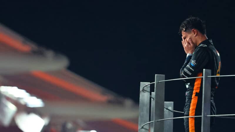 Lando Norris holds his head in his hands on the 2025 Abu Dhabi GP podium after winning the F1 world championship